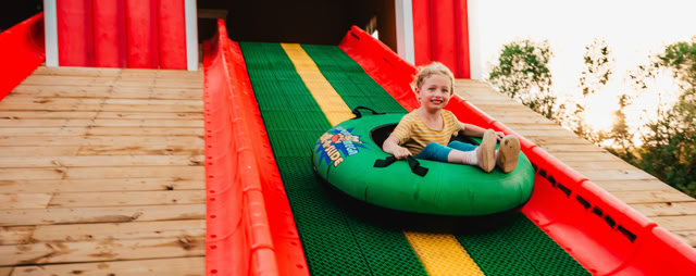 Child riding an inner tube down a large slide.