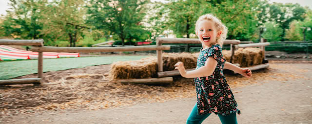 Child smiling and playing on a farmyard.