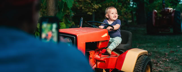 Small child pretending to drive a decorative farm tractor.